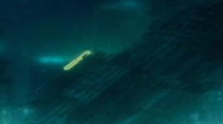 Small glowing object moving through deep blue water